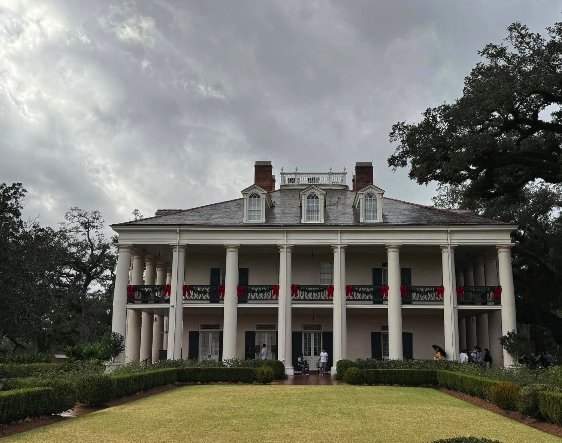 The front of the Oak Alley Big House with its colonnade of twenty-eight columns, dormer windows and twin chimneys under a grey sky